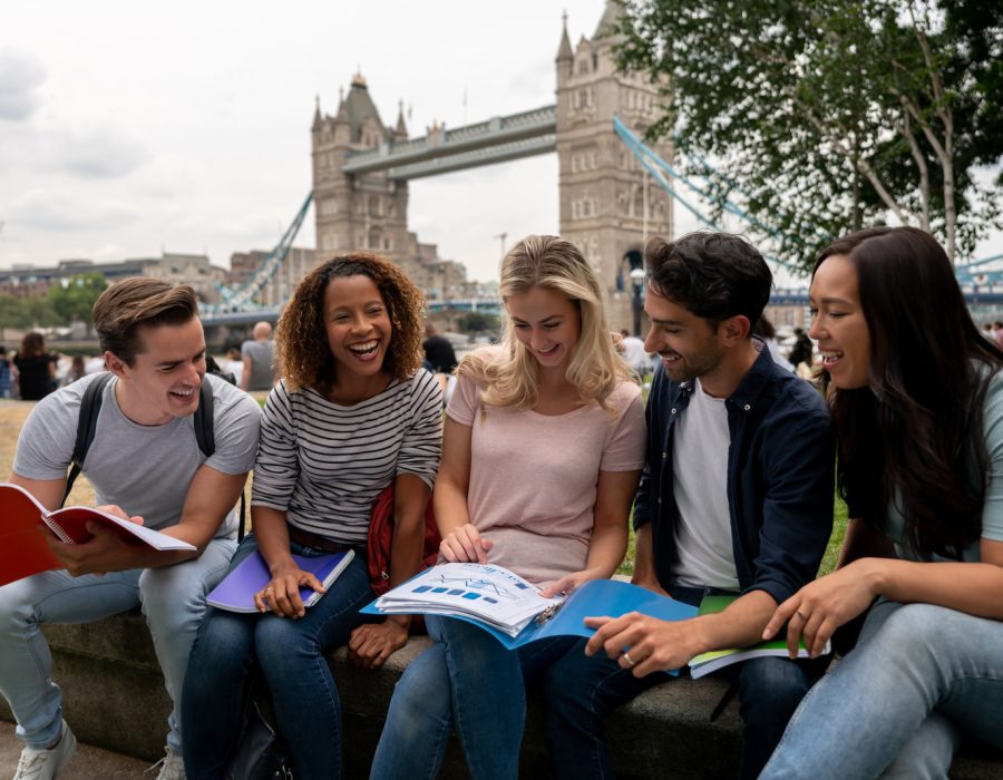 Happy group of post-graduate students studying outdoors in London - education concepts